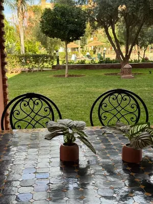 a table with two chairs and a table with plants on it at charmant appartement avec grande piscine & terrasse in Marrakech