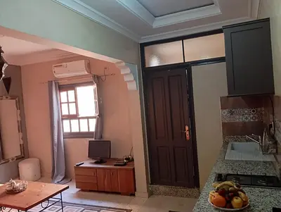 a kitchen with a door and a table with a bowl of fruit at appartement 6 min centre terrasse in Marrakech