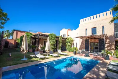 a swimming pool with chairs and umbrellas next to a house at Amelkis golf villa 3 ch private pool in Marrakech