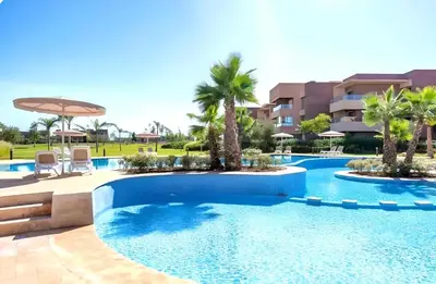 a pool at a resort with palm trees and chairs at Appartement de luxe prestigia agate Marrakech in Marrakech