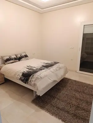 a white bedroom with a bed and a rug at Excellente appartement 3 chambres in Marrakech