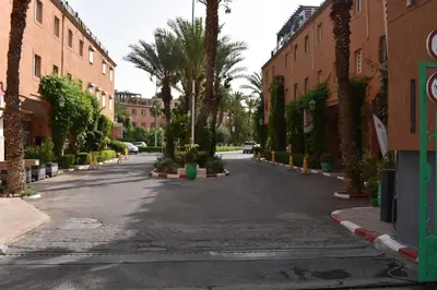 an empty street with palm trees and buildings at Riad Zaitone 135 in Marrakech