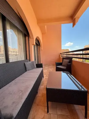a balcony with a couch and a table on a building at Luxurious appartement Marrakech - pool&terrace in Marrakech