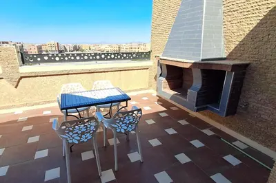 a table and chairs on a roof with a fireplace at Cozy, sunny apartment near the airport in Marrakech