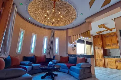 a living room with blue couches and a chandelier at Cozy, sunny apartment near the airport in Marrakech