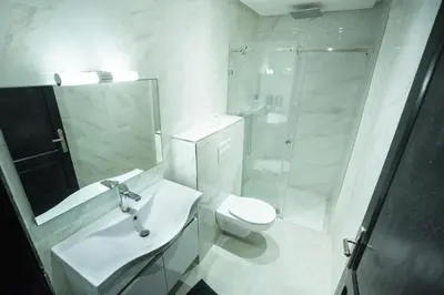 a white bathroom with a shower and a toilet at Villa Bonsai Marrakech in Marrakech