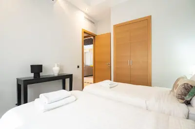 two white beds in a room with a closet at Appartement Cosy avec Parc et Piscine pour femme in Marrakech