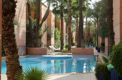 a courtyard with palm trees and a swimming pool at Palm Residence in Marrakech