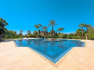a large swimming pool with palm trees in the background at Luxurious Duplex in a Peaceful Resort in Marrakech in Marrakech
