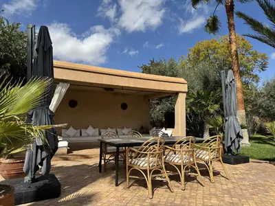a patio with a table and chairs and a couch at Villa Hilin - Piscine chauffée et hammam privé proche des golfs et du centre ville in Marrakech
