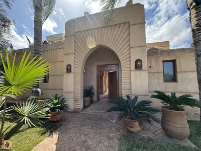 a building with palm trees in front of it at Villa Hilin - Piscine chauffée et hammam privé proche des golfs et du centre ville in Marrakech