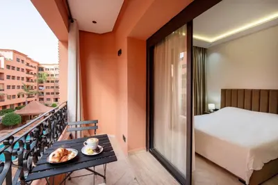 a balcony with a bed and a table with a plate of food at Résidence Babylone Y - Appartement Studio in Marrakech