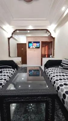 a living room with two beds and a tv on a wall at Saada 15 marrakech in Marrakech