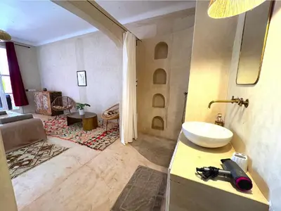 a bathroom with a sink and a living room at Palais Bohemia in El Rhechat