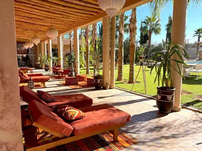 a patio with couches and tables and palm trees at Palais Bohemia in El Rhechat
