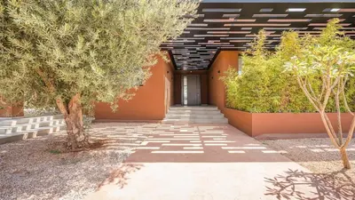 a walkway leading to a building with trees and bushes at Villa Luxe Padel in Marrakech