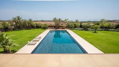 a swimming pool in a yard with a lawn with palm trees at Villa Luxe Padel in Marrakech