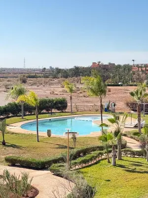 a swimming pool in the middle of a field with palm trees at Cosy Appartement Avec Piscine, Terrain tennis et loisirs in Marrakech