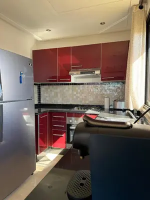 a kitchen with red cabinets and a stainless steel refrigerator at Cosy Appartement Avec Piscine, Terrain tennis et loisirs in Marrakech
