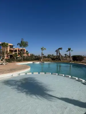 a large swimming pool in a resort with palm trees at Cosy Appartement Avec Piscine, Terrain tennis et loisirs in Marrakech