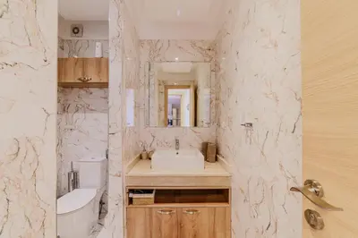 a bathroom with a sink and a toilet and a mirror at Coralia - Cozy Apartment - Secure residence - Pool in Marrakech