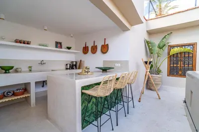 a kitchen with white walls and a counter with stools at Riad Sofia Marrakech in Marrakech