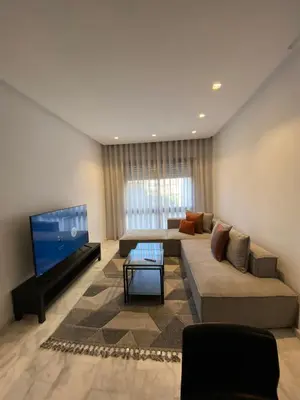 a living room with a couch and a flat screen tv at Chambre privée dans un appartement bien équipé in Marrakech