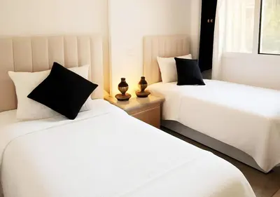 two beds with white sheets and black pillows in a room at Gate 3 in Marrakech