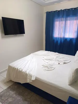 a bedroom with a white bed with a blue curtain at Magnifique studio douillet in Marrakech