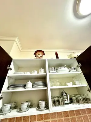 a white cabinet filled with dishes and plates at spacieux appart familial avec 2 chambres in Marrakech