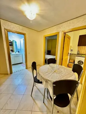 a dining room with a table and chairs and a kitchen at spacieux appart familial avec 2 chambres in Marrakech