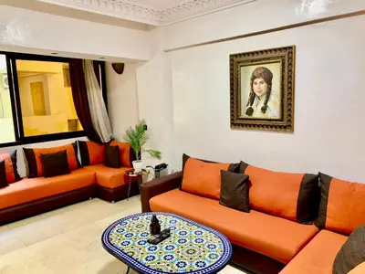 a living room with orange furniture and a painting on the wall at New Résidence Miramas 2 in Marrakech