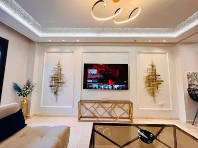 a living room with a couch and a tv on a wall at New Résidence Miramas 2 in Marrakech