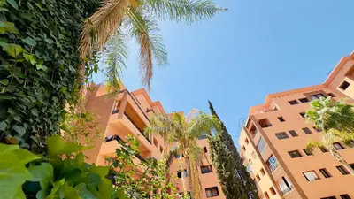 two tall buildings with palm trees in front of them at - Résidence Babylone Y - Appartement 3 Chambres in Marrakech