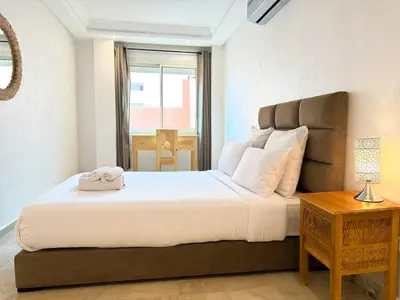 a bedroom with a large white bed and a table at Elegant 2-Bedroom Duplex Downtown Private Terrace in Marrakech