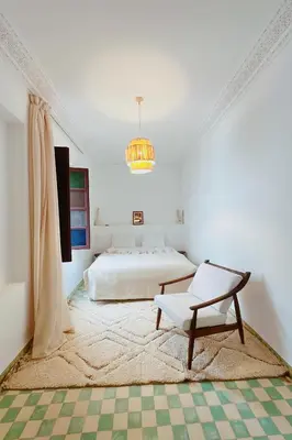 a white bedroom with a bed and a chair at Riad Solila, Fabuleux riad avec 4 Suites, Piscine Chauffée et Rooftop - 5 min de Jamaa El Fna in Marrakech