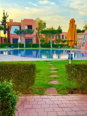 a yellow umbrella in the grass near a swimming pool at Appartement Belle vue sur l'atlas in Marrakech