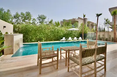a patio with a table and chairs next to a swimming pool at Villa Luxe 5 Suites & Piscine in Marrakech