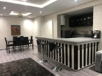 a kitchen and living room with a bar and chairs at APPARTEMENT MODERNE AU CENTRE m in Marrakech
