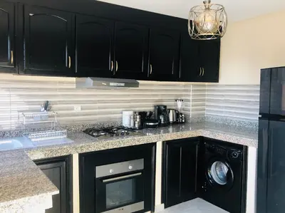 a kitchen with black cabinets and a washer and dryer at APPARTEMENT MODERNE AU CENTRE m in Marrakech