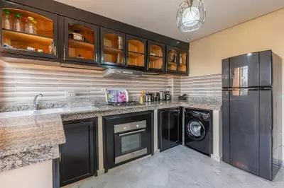 a kitchen with black cabinets and a washer and dryer at ELEGANT APARTMENT DOWNTOWN m in Marrakech