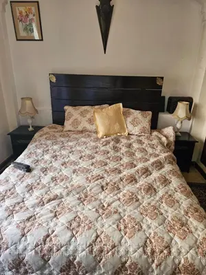 a bed with a brown and white comforter and two lamps at Warda-A-31 Rue Abi Hanifa in Marrakech