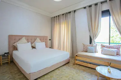 a bedroom with a large white bed and a couch at Villa Dar Cactus piscine chauffée in Marrakech