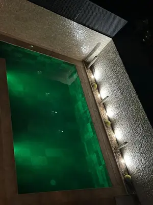 a swimming pool with lights on the side of a building at Villa Tazinsky in Hbl Hmid