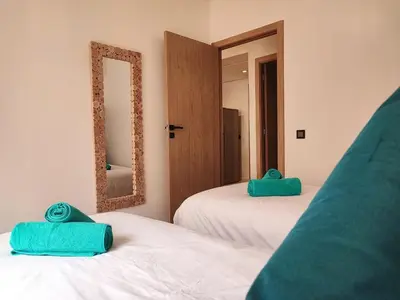 two green towels are sitting on two white beds at Stylish Apartment with Pool in Central Location Near Gueliz and Medina in Marrakech