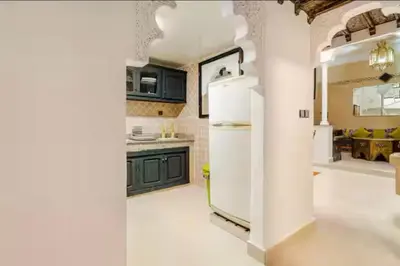 a kitchen with a white refrigerator and green cabinets at Riad Zitoune in Marrakech