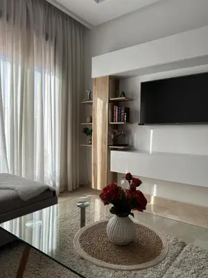 a living room with a vase with flowers on a glass table at Luxury apartment and free parking in Marrakech
