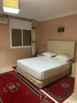a large white bed in a bedroom with a red rug at Asmae in Marrakech