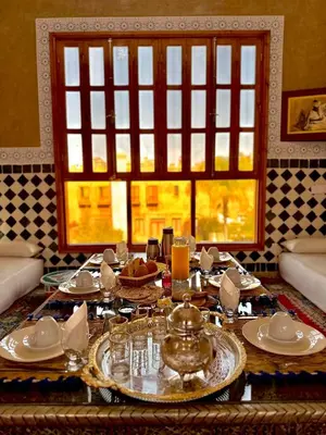 a dining room table with plates and a window at Riad Dar Mima Hnina - Your Traditional and Private haven of peace, 2 pools, 10' from airport in Marrakech