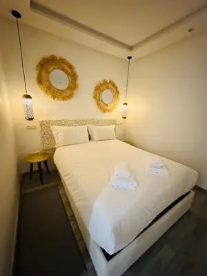 a bedroom with a large white bed with two mirrors at Cosy Appartement 2 Room Wifi Marrakech in Marrakech